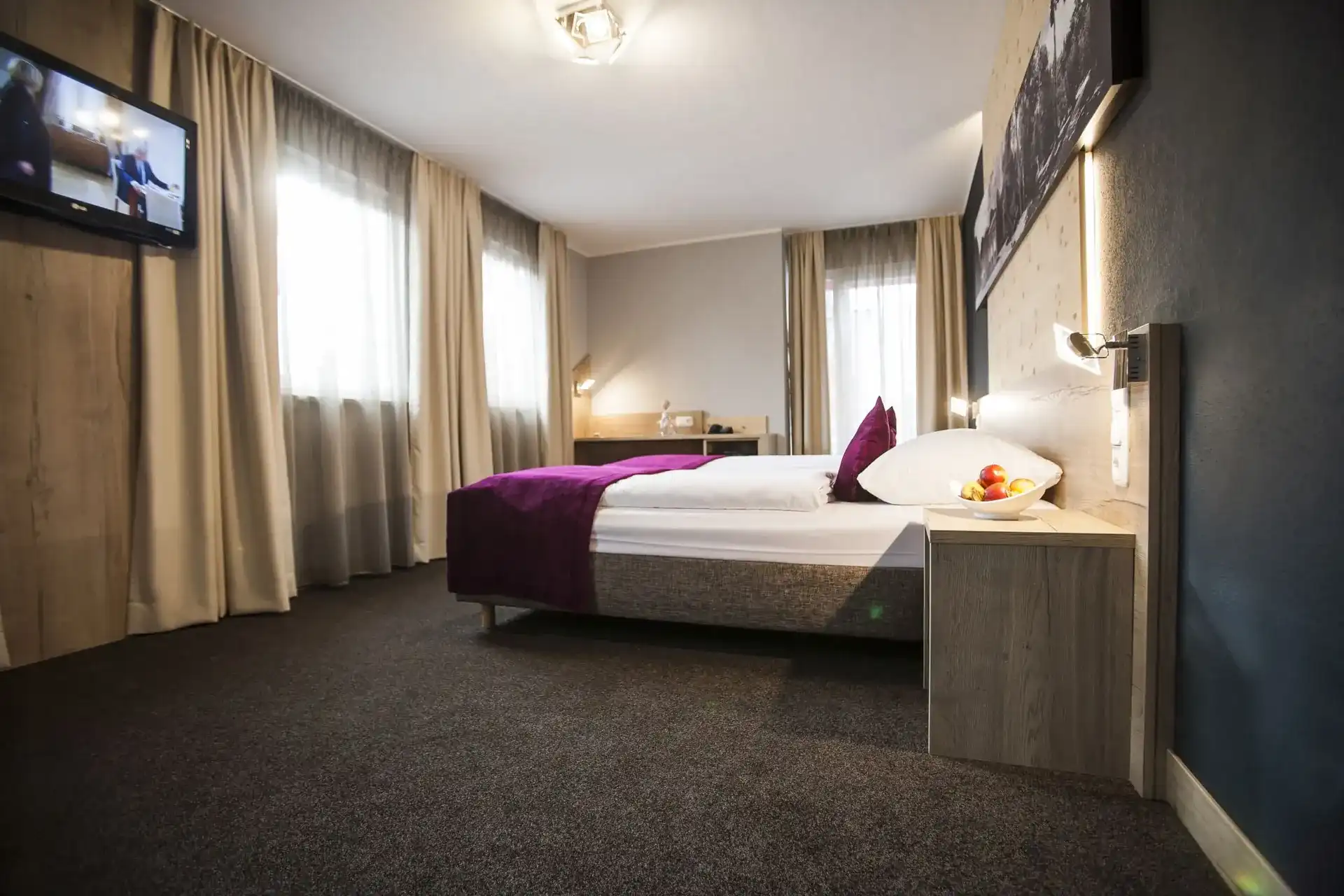 Zimmer mit dunkler Wand, Vorhängen und Doppelbett