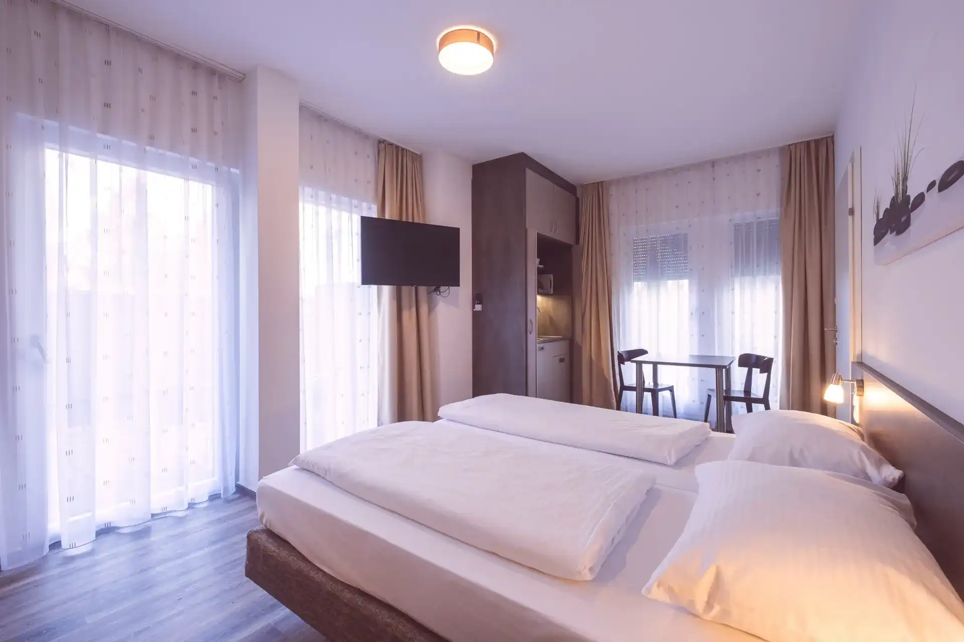 Comfort room with double bed, floor-to-ceiling windows, kitchenette and dining area